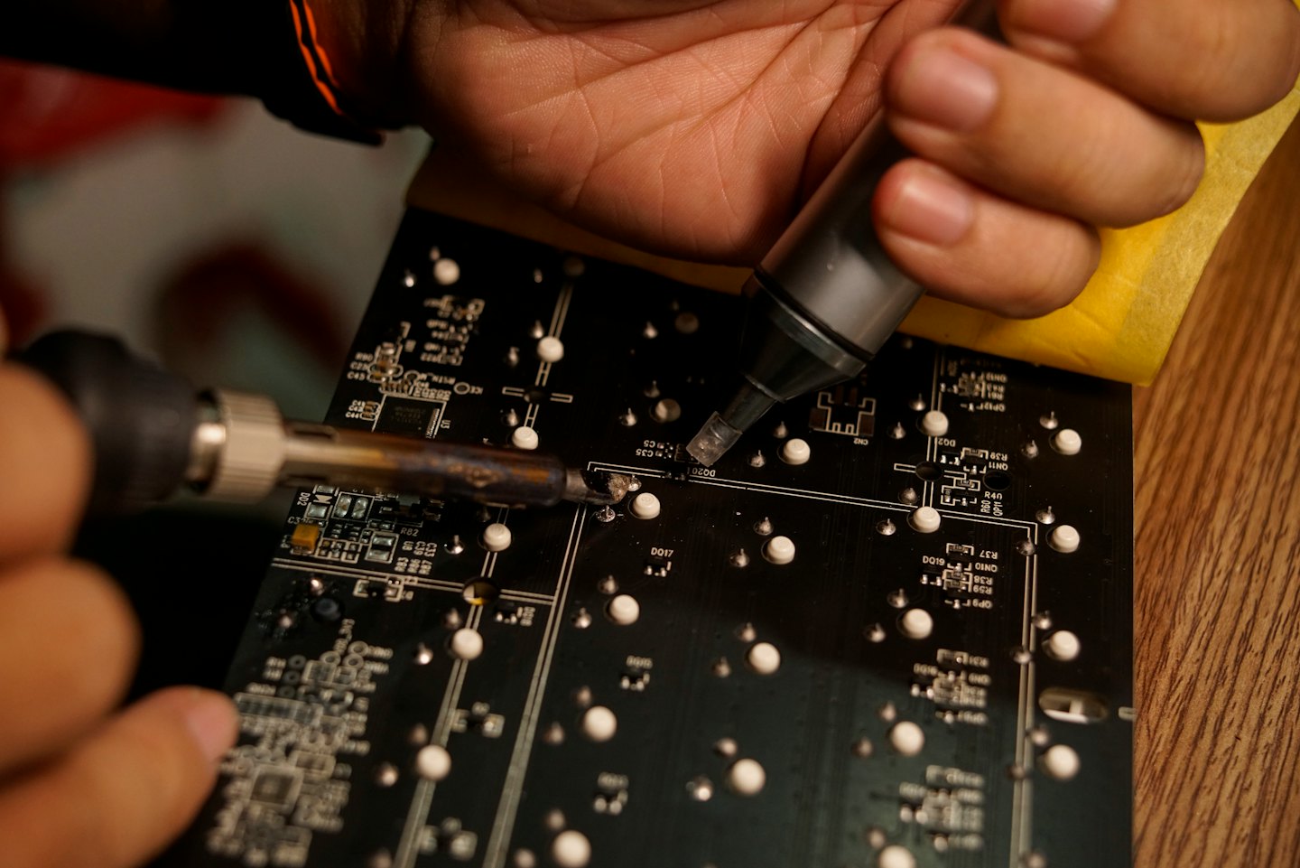 Hands soldering a circuit board with intricate electronics.