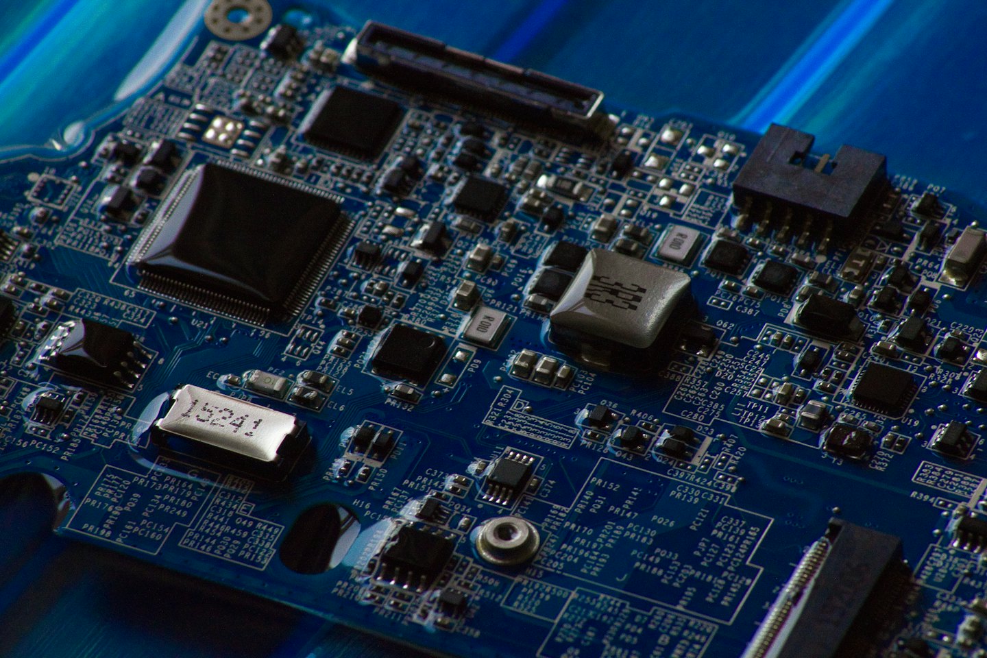 Electronic components and wiring on a blue circuit board.